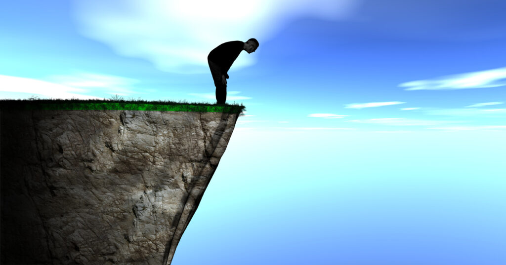 Man looking over the edge of cliff representing end of life or end of service